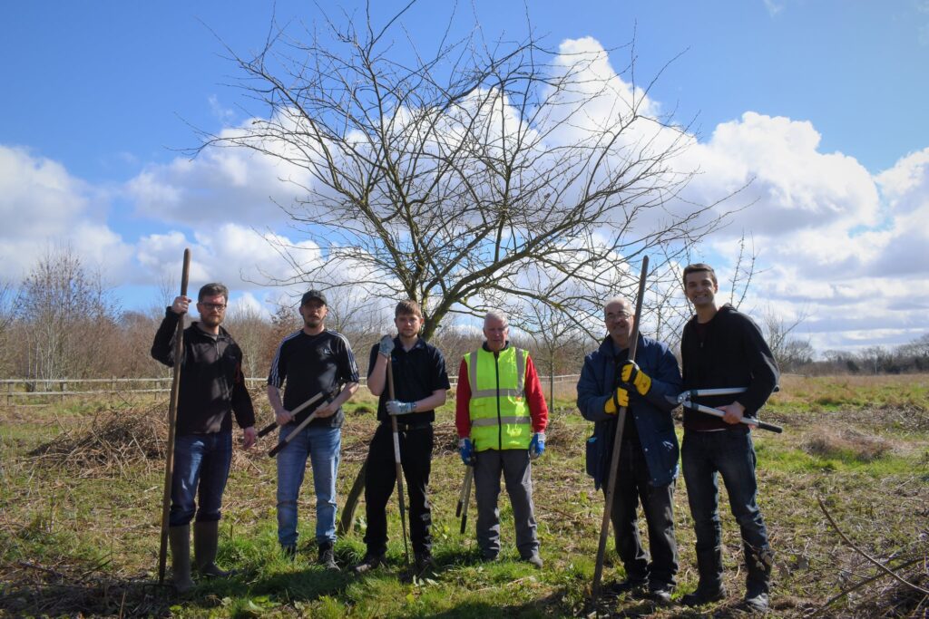 Phtograph of volunteers carrying tools posing for a photograph during a tidy up day.