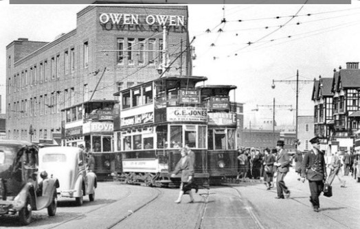 Monochrome image of three trams at the top of Trinity Street, with Owen Owen behind.