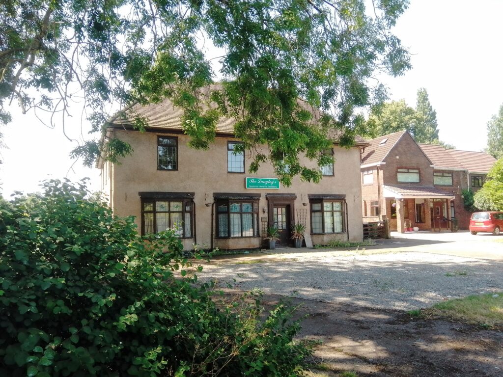 A colour photograph showing the Langleys on the left and a modern houre to its right. 