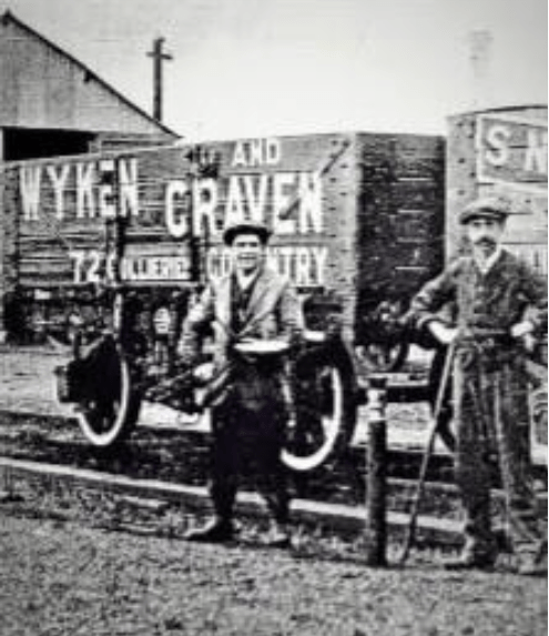 Old monochrome image showing a colliery wagon with two sorkers standing in front of it.