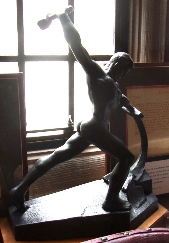Bronze statue of a muscular man striding forward, holding a hammer aloft and gripping a curved blade.