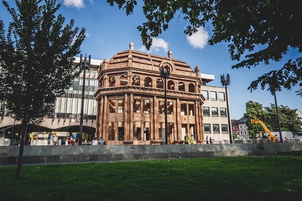 Image of a brown sgtructure with urban builings behind.